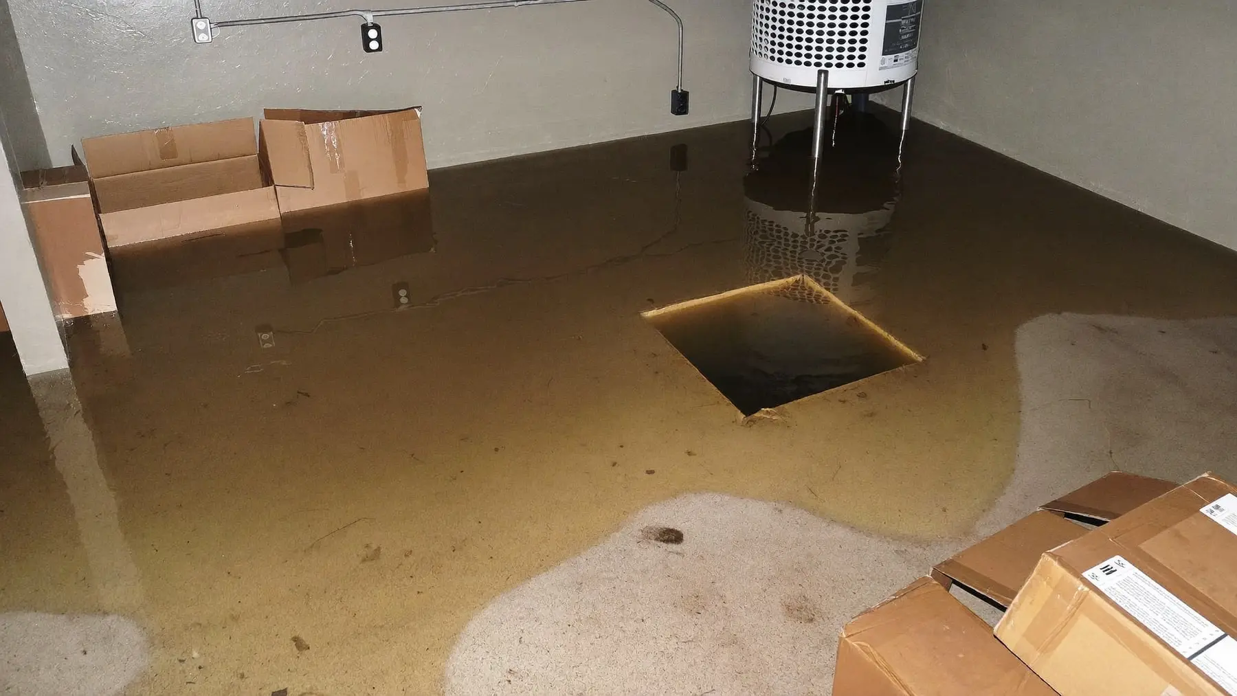 A flooded basement floor with water pooled around a sump pit