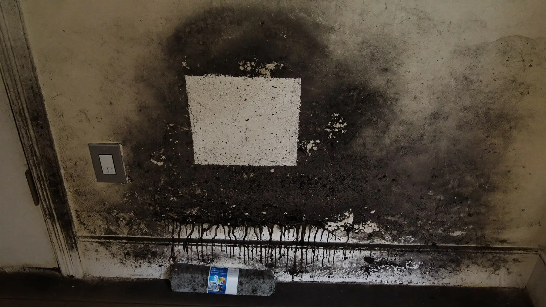 A chemical dry sponge lifting black soot from a painted wall, leaving a clean stripe