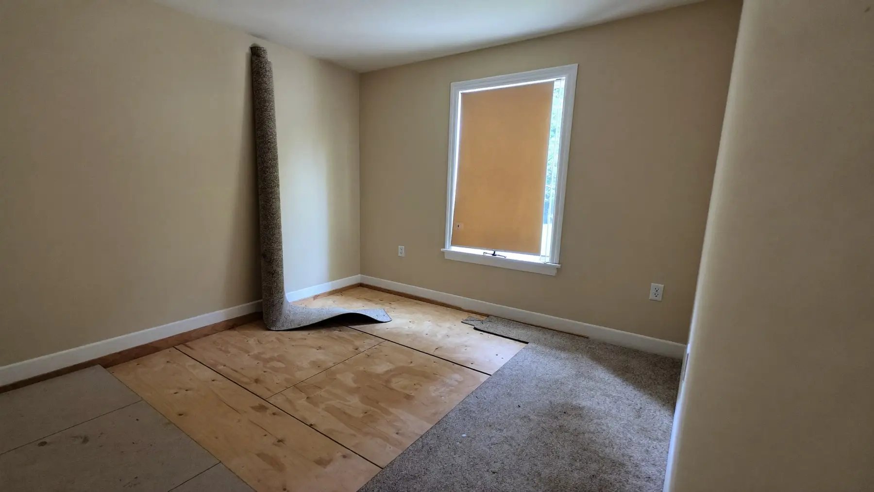 A room with the carpet and pad lifted and the subfloor exposed, ready for decontamination