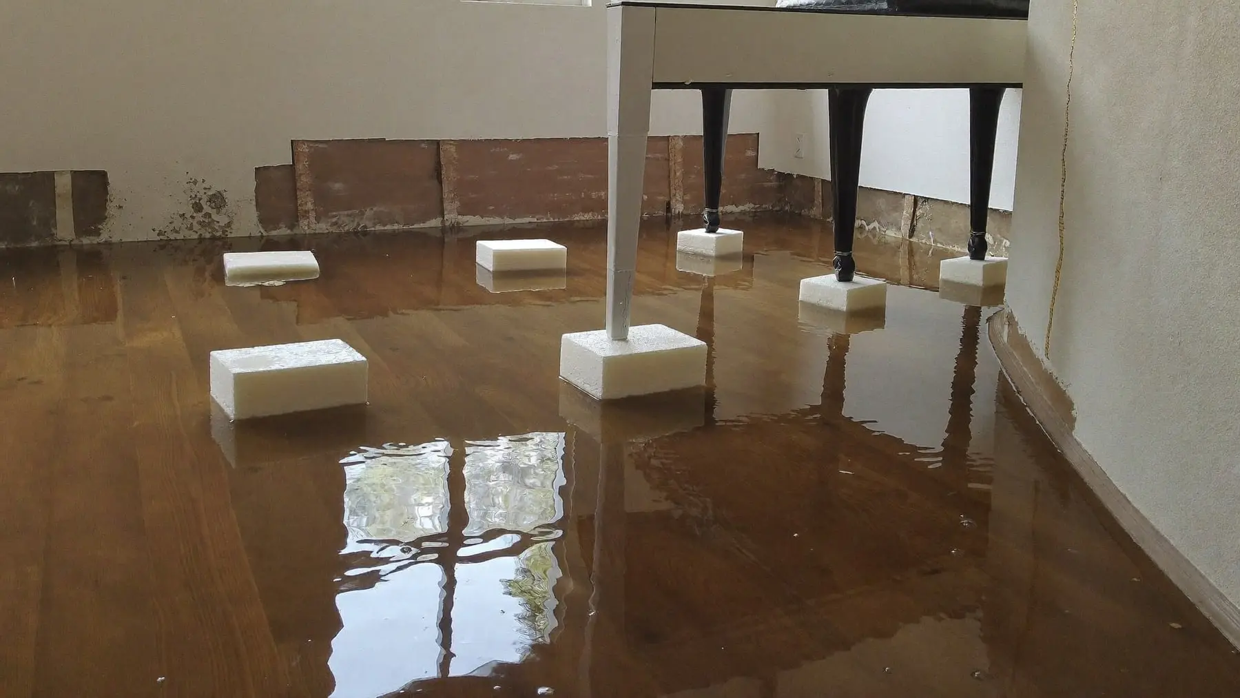 Standing water across a hardwood floor with furniture lifted onto blocks
